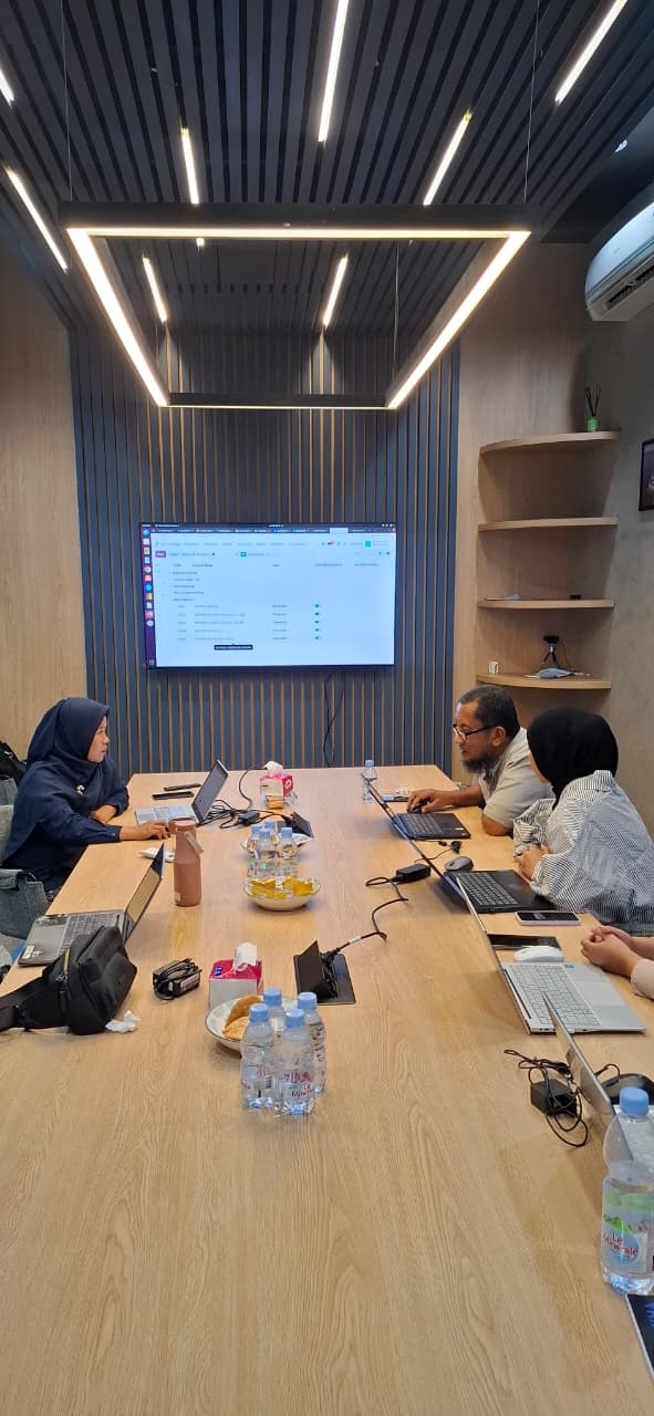 NURATEK and Casakha teams collaborating around a conference table during Odoo go-live preparation, with Odoo displayed on a wall screen