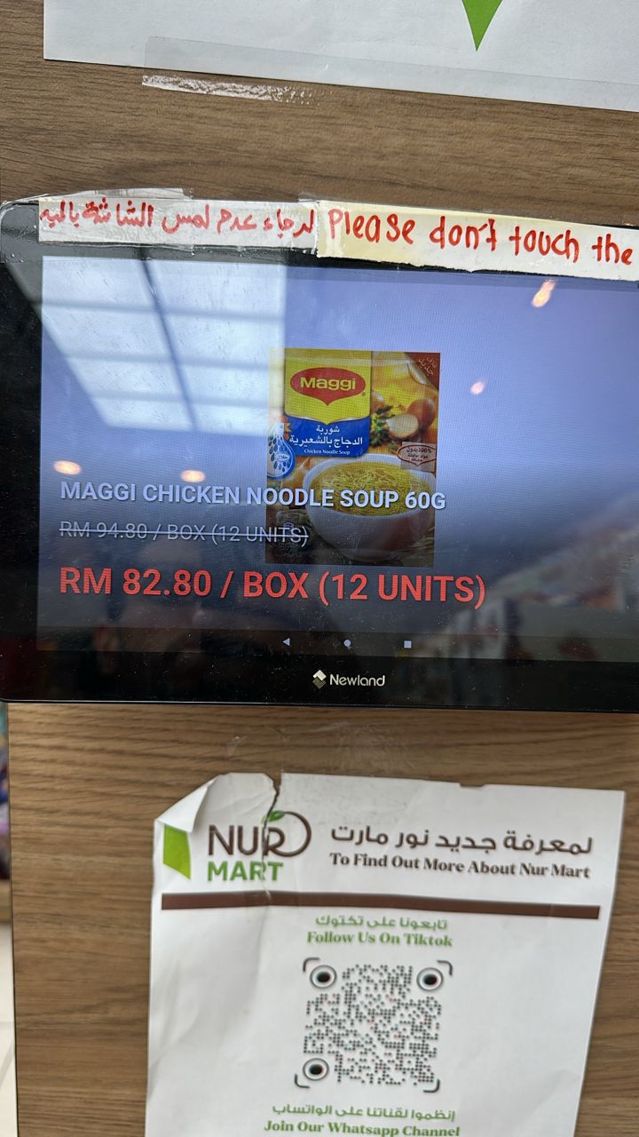 Tablet price checker di rak toko Nurmart menampilkan harga promo produk
