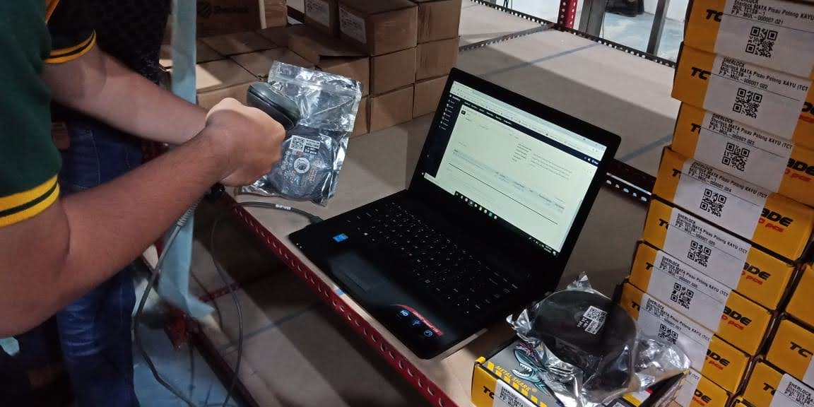Petugas gudang SherlockTools memindai kemasan perkakas dengan scanner genggam di samping laptop