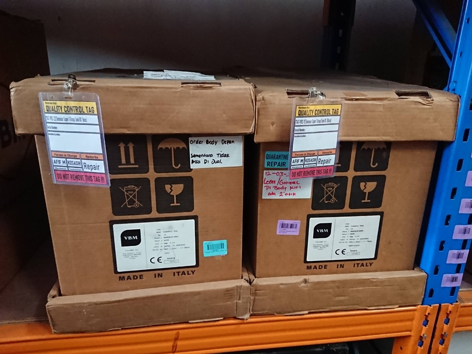 Dus produk di rak gudang dengan quality control tag bertanda karantina dan repair